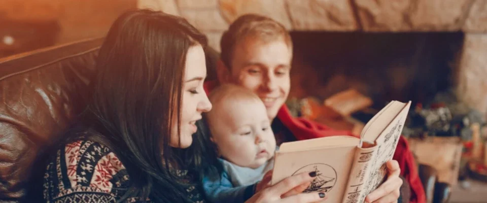 Mother and father reading a book with baby in the middle