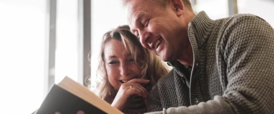 Senior couple laughing at book