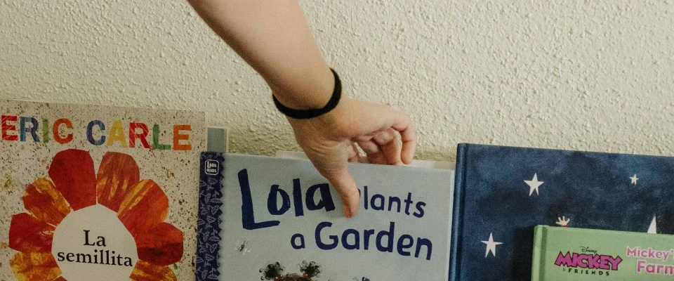 a person reaching for a book in a shelf