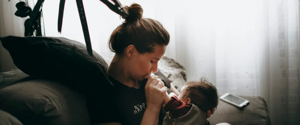 woman in black t-shirt sitting on the couch holding a baby