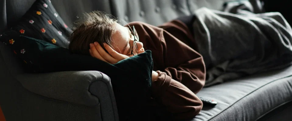 woman on pink jacket lying on gray couch