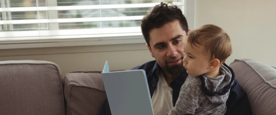 Father reading a book while holding his baby