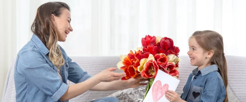Little daughter with flowers congratulates her mother