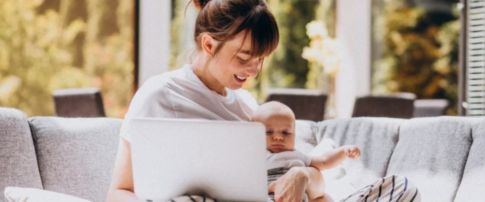 Young mother with her kid working at home on a computer