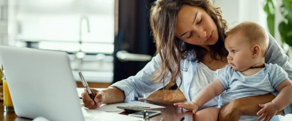 Young working mother planning home budget while being with her baby at home