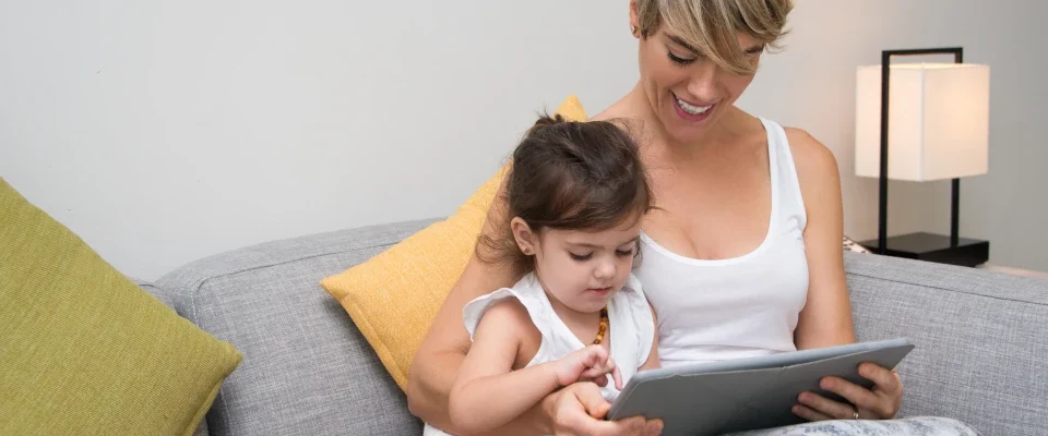 cheerful mother showing game tablet daughter